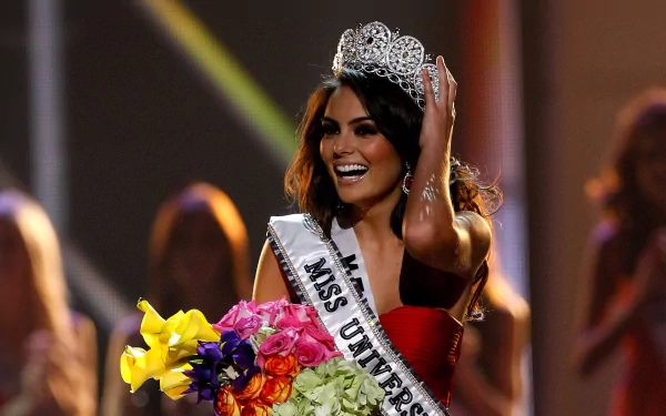 Ximena Navarrete, Mexican model and Miss Universe, smiling on stage with crown and sash, holding a bouquet of flowers in this HD PC desktop wallpaper.