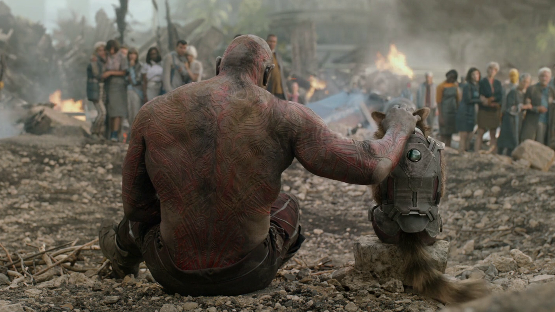 Drax the Destroyer, portrayed by Dave Bautista, sits alongside Rocket Raccoon amidst a dramatic scene from Guardians of the Galaxy, set against a chaotic background.