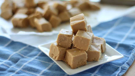 Close-up of creamy peanut butter fudge cubes stacked on a white plate, captured in sharp 4K Ultra HD quality, presented as a PC desktop wallpaper background.