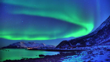 A stunning night scene of the aurora borealis illuminating the snowy landscape, showcasing vibrant green hues over a tranquil icy bay. 4K Ultra HD wallpaper for stunning visuals.