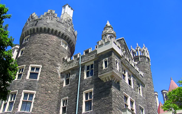 HD PC desktop wallpaper of Casa Loma — a man-made stone castle with turrets and towers rising against a vivid blue sky.