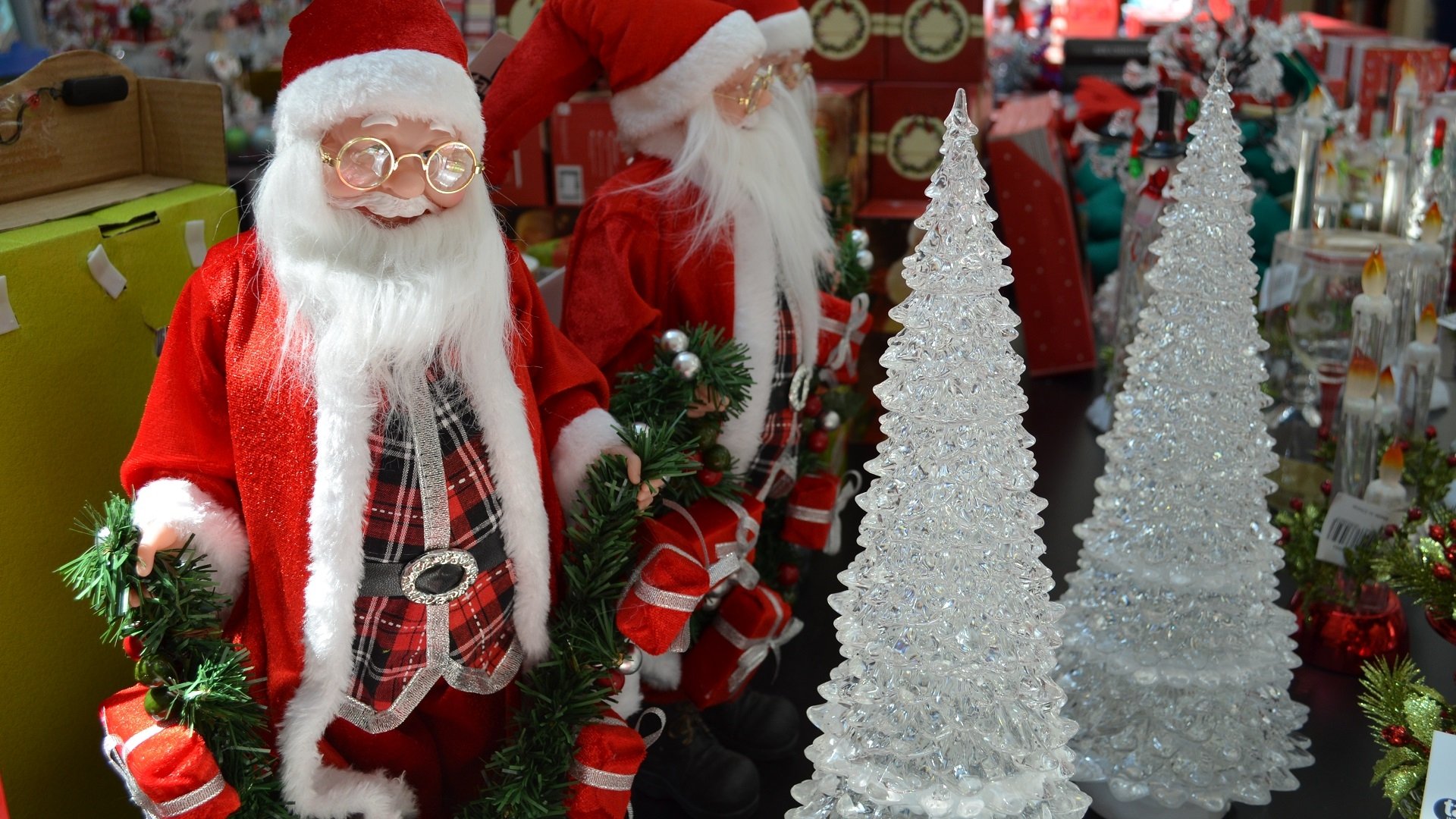 HD desktop wallpaper featuring a festive store display with Santa Claus figures, Christmas ornaments, and sparkling holiday decorations celebrating Christmas.
