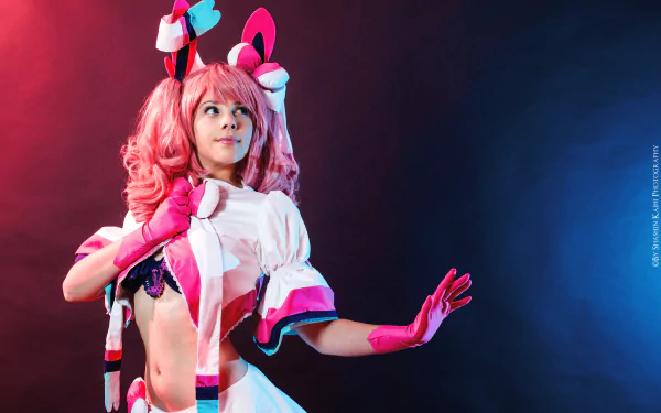 A woman in vibrant cosplay poses confidently against a dark background, featuring colorful lighting. An engaging HD desktop wallpaper showcasing creativity and character.