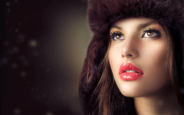 HD desktop wallpaper featuring a woman, tagged as Judy Wilkins, looking upwards with a neutral background. She is wearing a dark fur hat and has vibrant red lipstick.