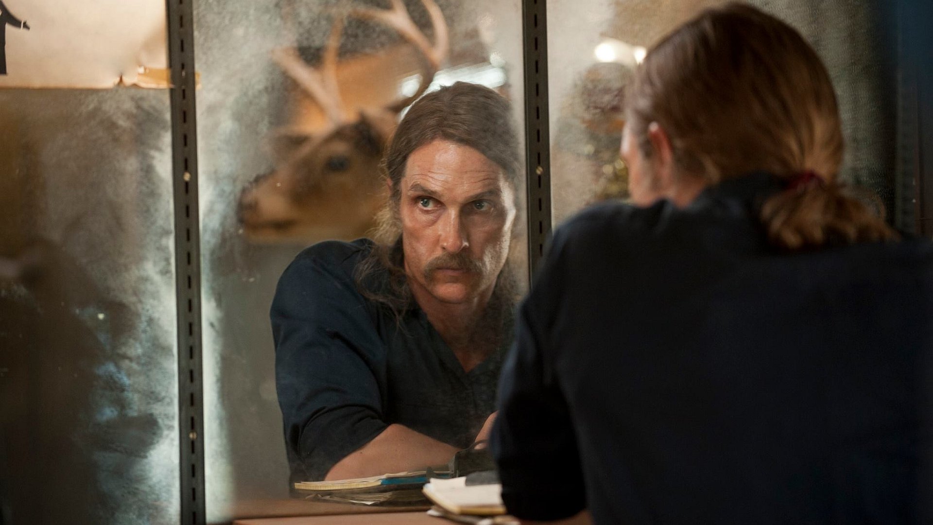 HD PC desktop wallpaper featuring a scene from the TV show True Detective with a man staring intently into a mirror in a dimly lit room.