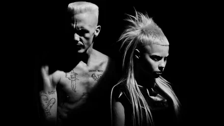 Black-and-white music HD PC desktop wallpaper/background: two moody performers — tattooed, shirtless man and intense woman with high ponytail, dramatic side lighting.