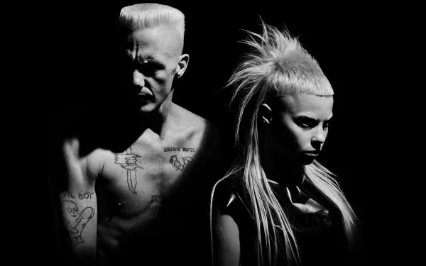 Black-and-white music HD PC desktop wallpaper/background: two moody performers — tattooed, shirtless man and intense woman with high ponytail, dramatic side lighting.