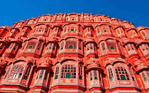 A vibrant HD wallpaper showcasing the intricate façade of Hawa Mahal, the iconic palace in Jaipur, India, featuring its beautiful red sandstone and numerous ornate windows against a clear blue sky.