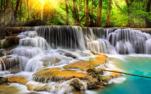 Erawan Waterfall in Erawan National Park, Tenasserim Hills, Thailand, showcases cascading waters surrounded by lush greenery, creating a serene natural landscape.