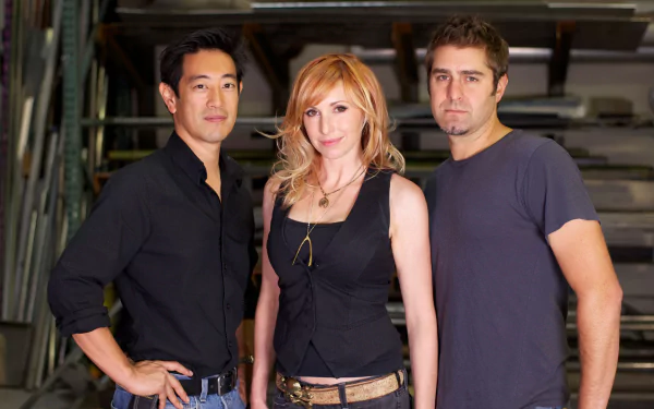 HD PC desktop wallpaper: three people stand in a workshop, posed for a MythBusters TV-show–themed background.