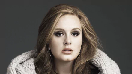 Adele, a renowned British singer, appears in this HD desktop wallpaper, showcasing her striking features and captivating presence against a dark background.