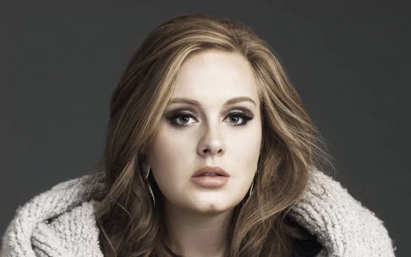 Adele, a renowned British singer, appears in this HD desktop wallpaper, showcasing her striking features and captivating presence against a dark background.
