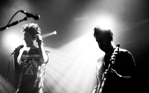 Black and white 4K Ultra HD wallpaper of English rock band Bastille performing live, featuring dramatic stage lighting and dynamic silhouettes.