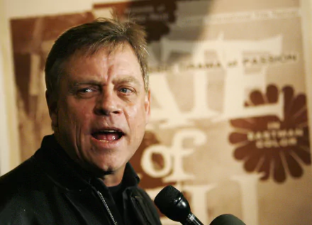 HD desktop wallpaper featuring a photo of Mark Hamill at an event, with a backdrop that includes a logo.