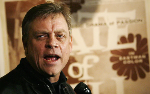 HD desktop wallpaper featuring a photo of Mark Hamill at an event, with a backdrop that includes a logo.