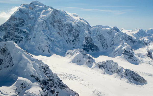 Snow-covered mountain peaks in Alaska during winter, captured in stunning 4K Ultra HD showcasing the pristine natural beauty of the snowy mountain landscape.
