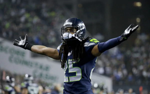Seattle Seahawks player celebrates with arms outstretched on the field, blurred crowd behind — 5K Ultra HD PC desktop wallpaper sports background.