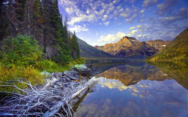 Crystal-clear waters of Lake Josephine in Montana reflect rugged mountains and lush pine forests under a vibrant sky, captured in stunning 4K Ultra HD detail.
