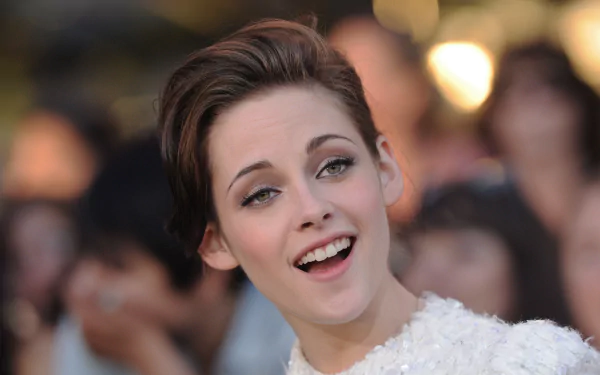 A captivating HD wallpaper featuring Kristen Stewart, showcasing her joyful expression amidst a blurred background of fans at a lively event.