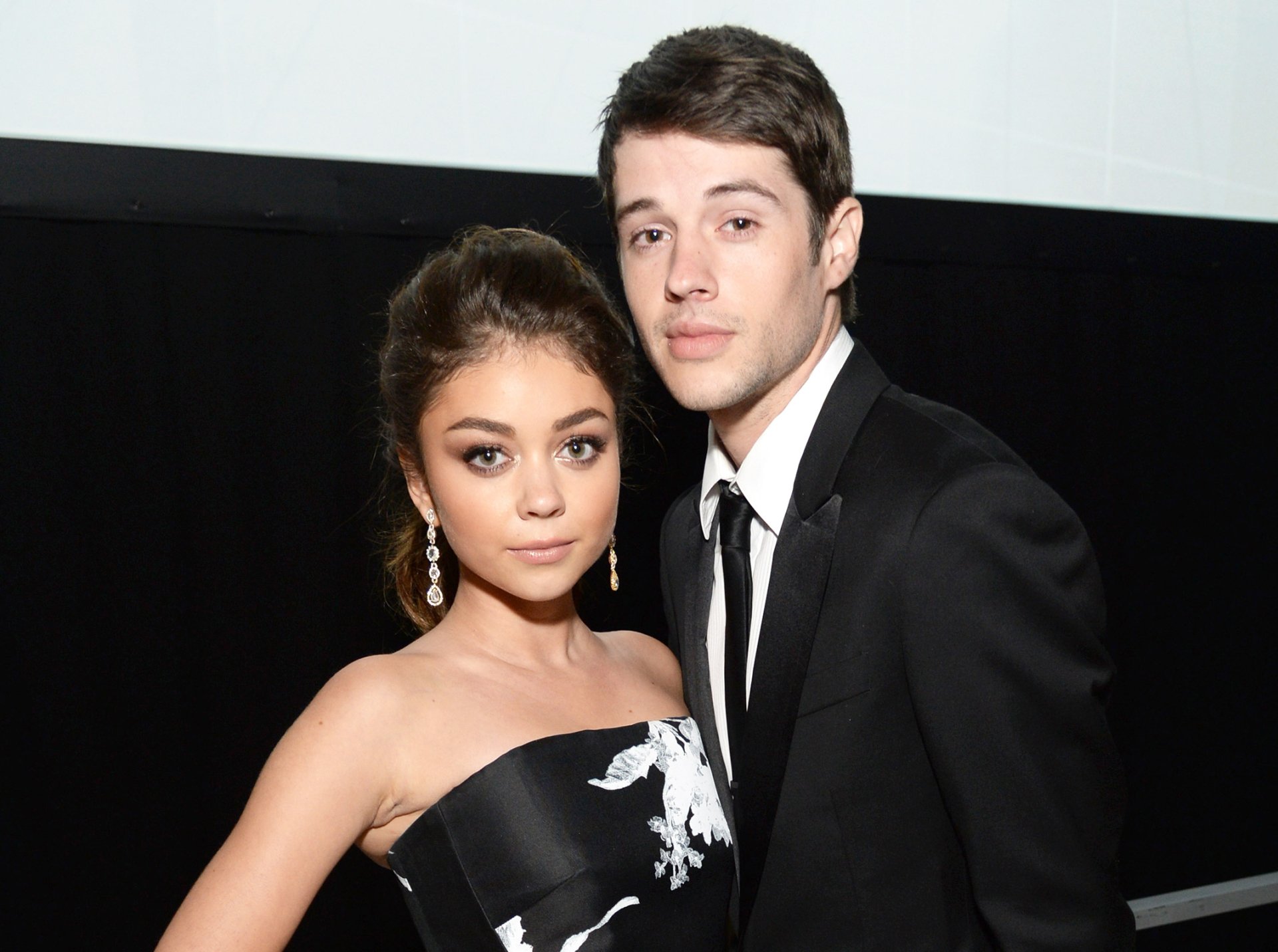 HD desktop wallpaper featuring celebrity Sarah Hyland posing elegantly with a partner, both dressed in formal attire against a dark background.