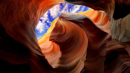 HD desktop wallpaper featuring the vibrant orange curves of Antelope Canyon contrasted with a vivid blue sky.