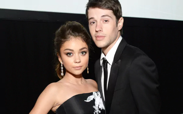 HD desktop wallpaper featuring celebrity Sarah Hyland posing elegantly with a partner, both dressed in formal attire against a dark background.