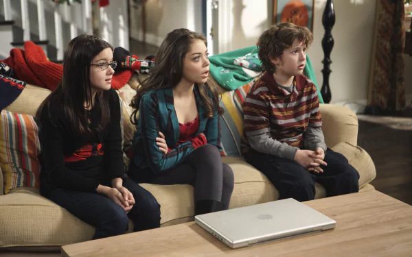 HD desktop wallpaper of three young Modern Family characters sitting on a couch.