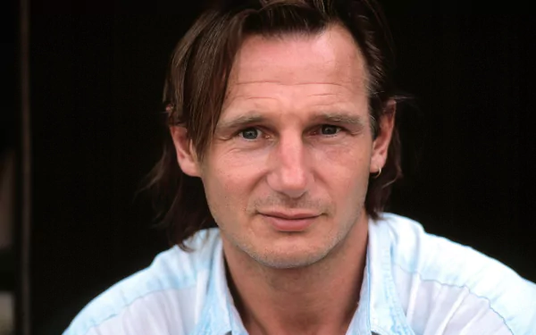 HD desktop wallpaper featuring a close-up of a man with medium-length hair, wearing a light blue shirt, with a subtle smile.