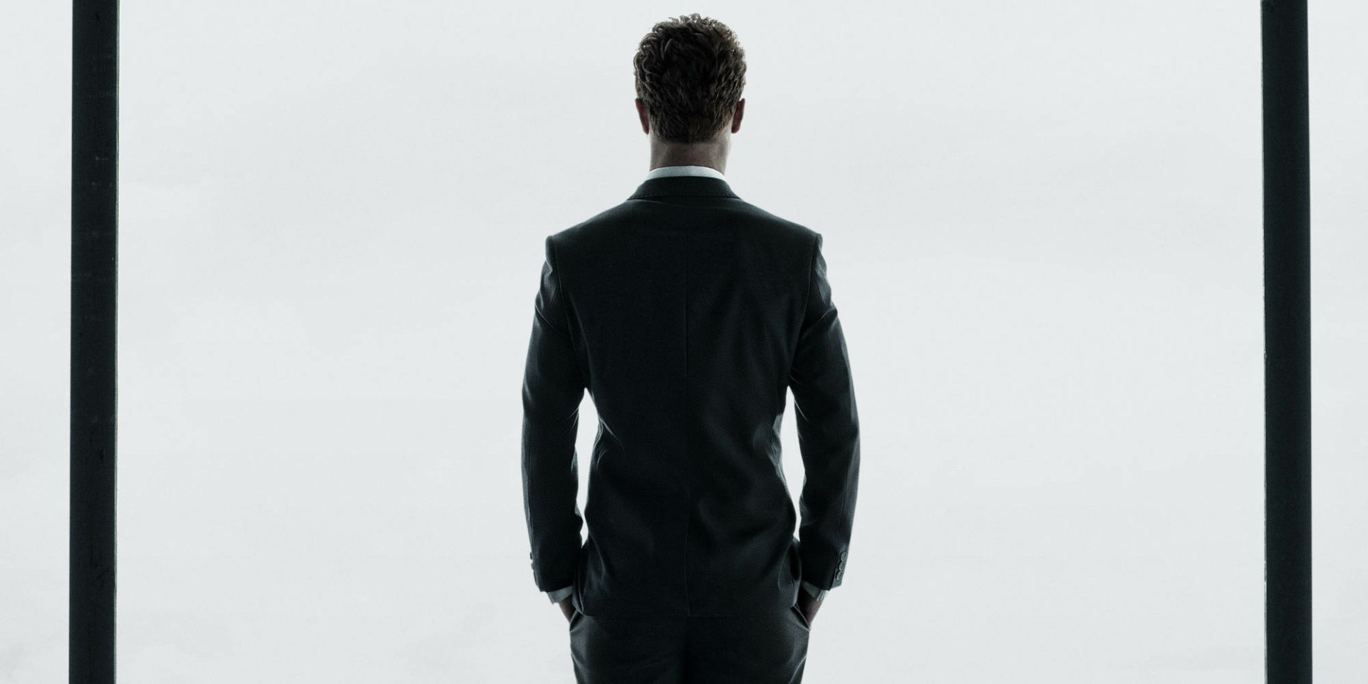 HD wallpaper of a man from Fifty Shades of Grey, possibly Jamie Dornan, standing with his back to the camera in a suit.