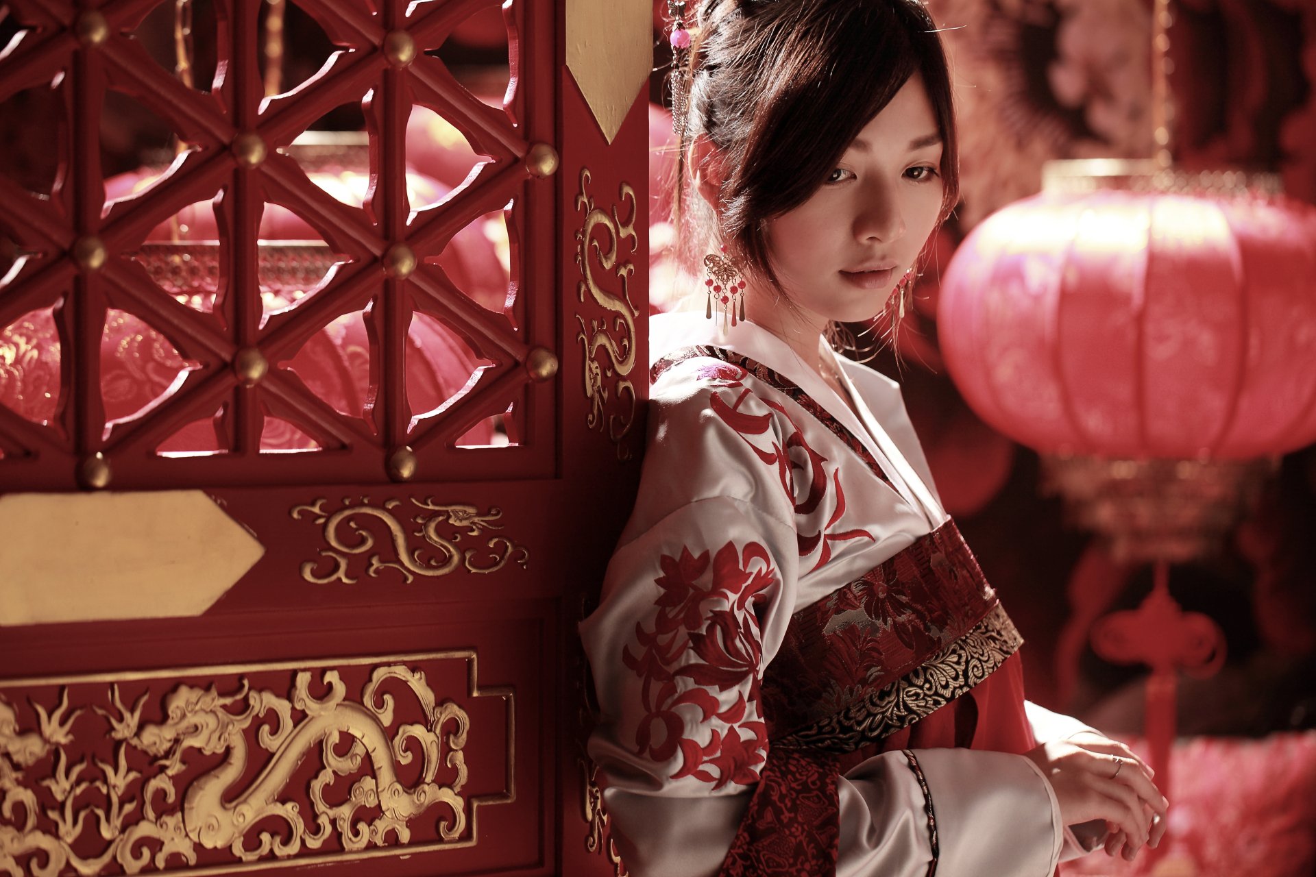 A Taiwanese woman in traditional national dress stands beside an ornate red door and a glowing lantern, captured in a detailed 4K Ultra HD wallpaper.