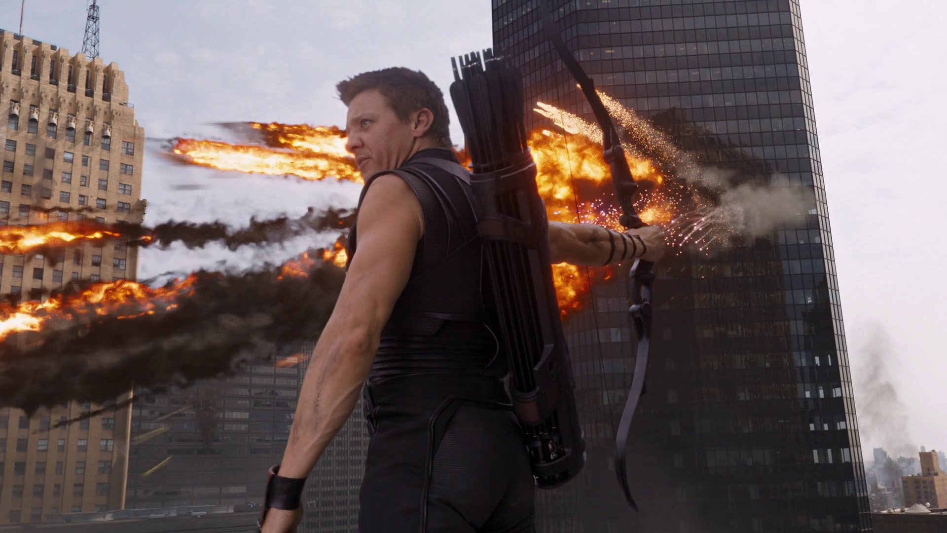 HD PC desktop wallpaper featuring Jeremy Renner as Hawkeye from the Avengers movie, poised with his bow against a fiery city backdrop.