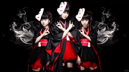 Three female metal idols, dressed in black and red outfits with traditional Japanese elements, pose against a dark background, embodying the vibrant energy of Babymetal in a heavy metal theme.