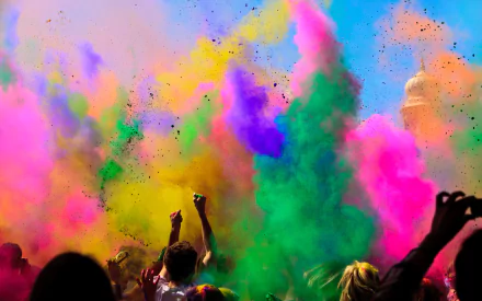 A vibrant HD wallpaper capturing people celebrating Holi with colorful powders in the air. The lively scene features an array of colors, embodying the festive spirit and joy of the holiday.