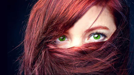 HD PC desktop wallpaper: close-up of a woman's vivid green eyes peeking through flowing red hair, strands sweeping across her face and framing an intense, mysterious gaze.