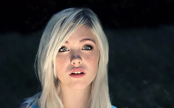 A close-up of a woman with blonde hair and striking blue eyes, set against a dark background, creates an engaging HD desktop wallpaper featuring Devon Jade.