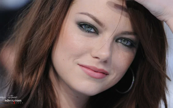 Close-up of Emma Stone, showcasing her striking green eyes and warm smile. This high-definition image serves as a captivating desktop wallpaper and background.