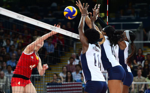 A dynamic volleyball match in action, showcasing intense competition as a player spikes the ball over the net, surrounded by eager defenders. HD desktop wallpaper for sports enthusiasts.