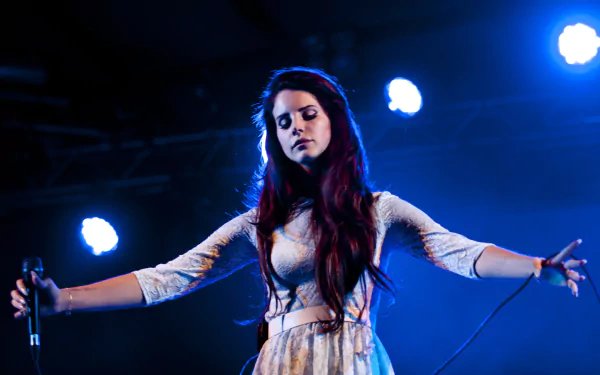 HD desktop wallpaper featuring Lana Del Rey performing on stage with a microphone, set against a blue-lit background highlighting her music presence.