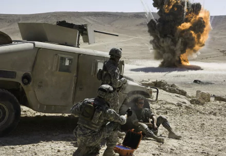 HD desktop wallpaper of a scene from the movie The Hurt Locker showing soldiers near a military vehicle with a large explosion in the background.