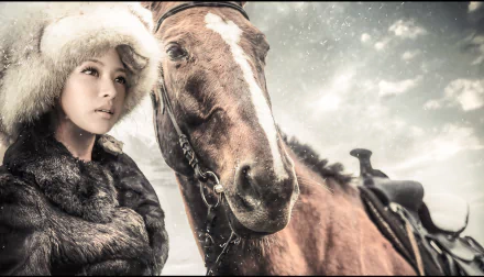 2K Quad HD PC desktop wallpaper: a fur-trimmed woman model beside a saddled horse amid soft snowfall, cinematic winter portrait background.