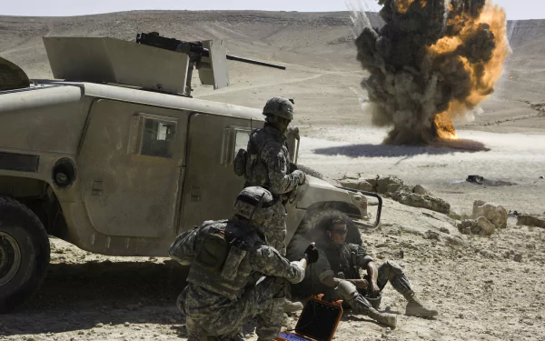 HD desktop wallpaper of a scene from the movie The Hurt Locker showing soldiers near a military vehicle with a large explosion in the background.