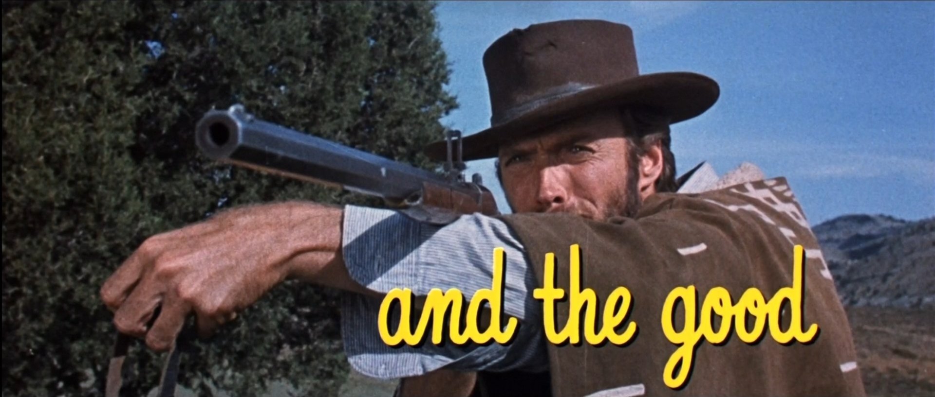HD desktop wallpaper of a tense Western scene from The Good, the Bad and the Ugly: a hat-wearing man aiming a rifle with bold yellow movie title text across the image.