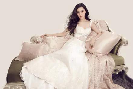 A stunning image of actress Fan Bingbing lounging elegantly on a couch, wearing a delicate white dress, complemented by soft pillows, captured in 4K Ultra HD quality.