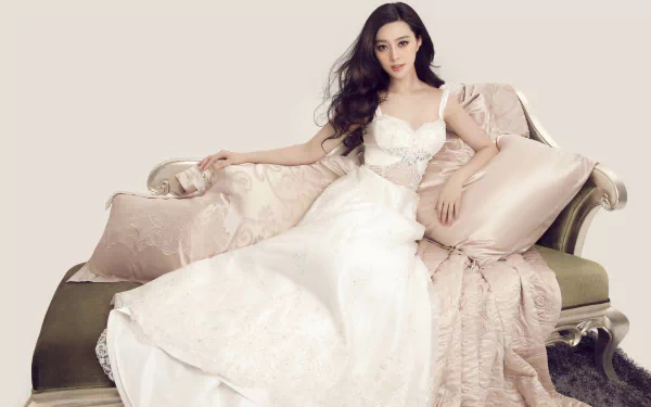 A stunning image of actress Fan Bingbing lounging elegantly on a couch, wearing a delicate white dress, complemented by soft pillows, captured in 4K Ultra HD quality.