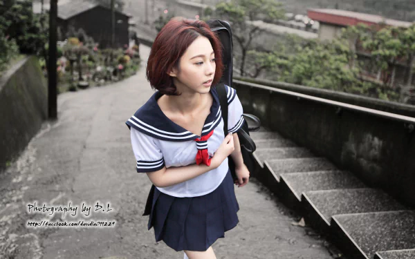 A Taiwanese woman in a school uniform stands on a flight of concrete stairs. The image is an HD desktop wallpaper featuring model Lín Yǔ walking.