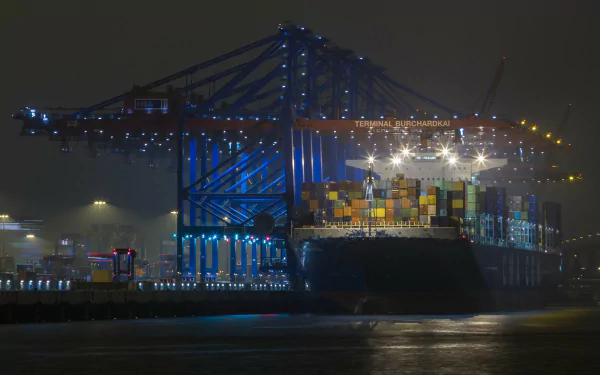 A brightly lit container ship docked at night, showcasing colorful cargo containers and illuminated cranes, serving as a striking HD desktop wallpaper and background.
