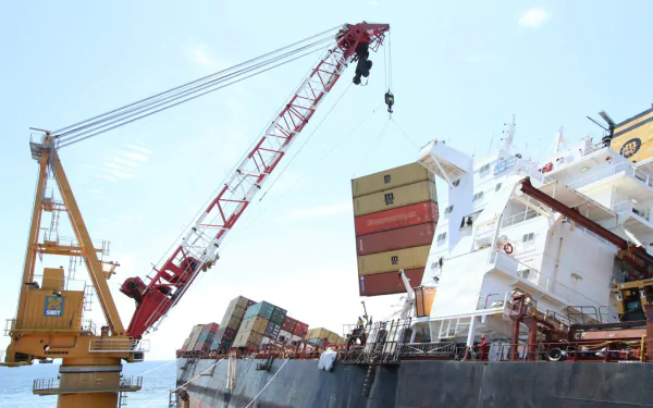 A vibrant HD wallpaper featuring a container ship being loaded with colorful cargo, showcasing a busy dock scene with a crane in action against a clear sky.