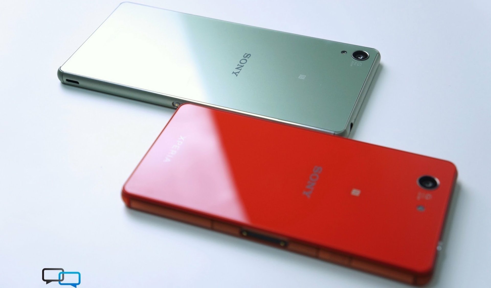 Two glossy phones, red and silver, lying back-to-back on a white surface; technology phone HD PC desktop wallpaper background.