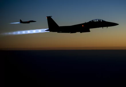 Silhouetted McDonnell Douglas F-15 Eagle fighter jets with afterburners glowing, flying at dusk against a darkening sky in this HD military desktop wallpaper.
