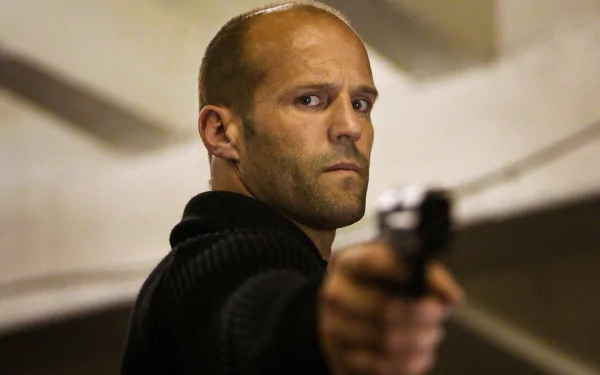 HD PC wallpaper: close-up of a bald action actor aiming a handgun in a tense movie scene, Hummingbird movie–style background.